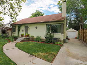 View of front of property featuring a tile roof, an outdoor structure, a detached garage, brick siding, and driveway
