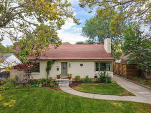 Ranch-style home with a tile roof, a chimney, and brick siding