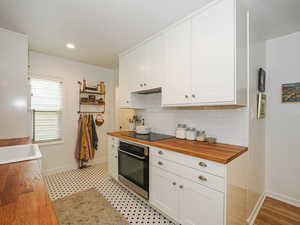 Kitchen with white cabinetry, wood counters, oven, decorative backsplash, and recessed lighting