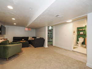 Living room featuring light colored carpet, a textured ceiling, and recessed lighting
