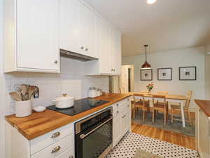 Kitchen featuring wooden counters, white cabinets, stainless steel oven, tasteful backsplash, and recessed lighting