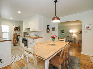 Dining area featuring arched walkways, light wood finished floors, and recessed lighting