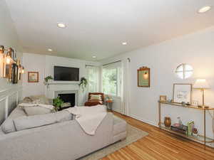 Living area featuring ornamental molding, light wood-type flooring, a tile fireplace, and recessed lighting