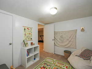Bedroom featuring light colored carpet and a textured ceiling