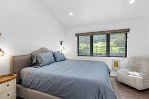 Bedroom with wood finished floors, recessed lighting, and vaulted ceiling