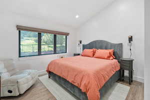Bedroom featuring vaulted ceiling, recessed lighting, and wood finished floors