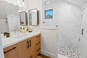On suite bathroom featuring vanity and a marble finish shower