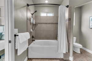 Bathroom featuring shower / tub combo with curtain and baseboards