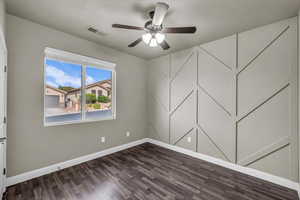 Spare room with dark wood-style floors and a ceiling fan