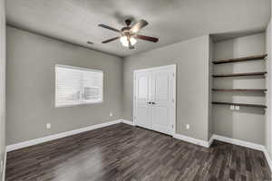 Unfurnished bedroom featuring dark wood-style flooring, ceiling fan, and a closet