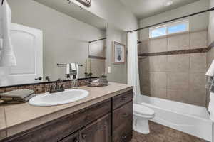 Bathroom with vanity, shower / bath combo, and dark tile patterned floors