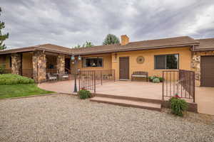 Single story home with a patio, a chimney, an attached garage, and brick siding