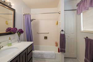 Bathroom featuring shower / bath combo with shower curtain, vanity, and a closet