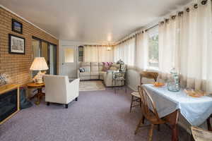 Living room featuring carpet, brick wall, and a chandelier