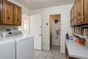 Laundry room featuring cabinet space, washing machine and clothes dryer, and light tile patterned floors