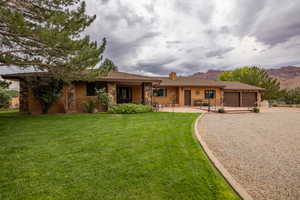 Ranch-style home featuring an attached garage, a front yard, concrete driveway, a chimney, and stone siding