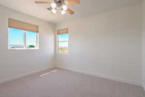 Carpeted empty room featuring baseboards and ceiling fan