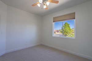 Carpeted spare room featuring baseboards and a ceiling fan