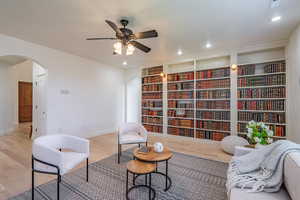 Living area featuring wood finished floors, arched walkways, recessed lighting, and a ceiling fan