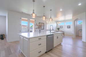 Kitchen with hanging light fixtures, white cabinetry, light wood finished floors, an island with sink, and recessed lighting