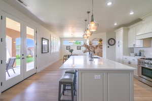 Kitchen with white cabinetry, decorative backsplash, light wood-style floors, stainless steel range, and recessed lighting