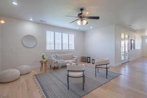 Living area with healthy amount of natural light, light wood-style floors, recessed lighting, and ceiling fan