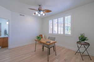 Office with light wood-style flooring and ceiling fan