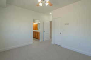 Unfurnished bedroom featuring light carpet, ceiling fan, and connected bathroom