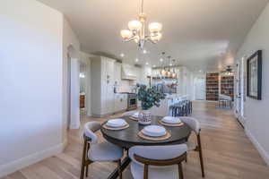 Dining space with arched walkways, light wood-style flooring, and a chandelier