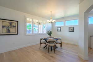 Dining space with light wood-style floors, arched walkways, and a chandelier
