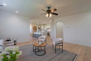 Living room with light wood-style flooring, arched walkways, recessed lighting, and ceiling fan