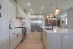 Kitchen with high end appliances, tasteful backsplash, decorative light fixtures, recessed lighting, and light stone counters