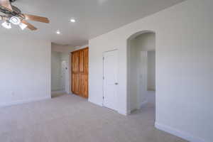 Unfurnished room with arched walkways, light carpet, recessed lighting, and ceiling fan