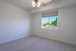 Carpeted empty room featuring baseboards and a ceiling fan