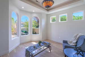 Sitting room with light wood finished floors, a tray ceiling, and recessed lighting