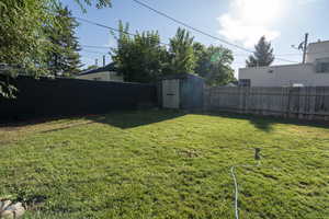 Fenced backyard featuring a storage unit