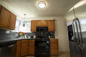 Kitchen with appliances with stainless steel finishes, brown cabinets, tasteful backsplash, and a textured ceiling