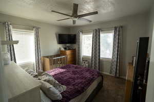Bedroom with a textured ceiling, carpet flooring, and a ceiling fan
