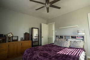Carpeted bedroom featuring a textured ceiling and a ceiling fan