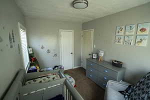 Bedroom with a textured ceiling and dark colored carpet