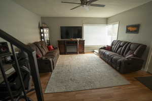 Living area featuring light wood finished floors, ceiling fan, and a textured ceiling
