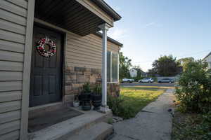 Entrance to property with stone siding and a yard