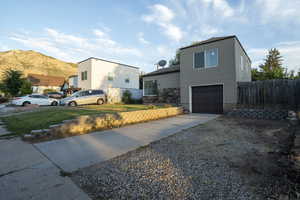 View of front of property with a garage, driveway, a mountain view, and stone siding