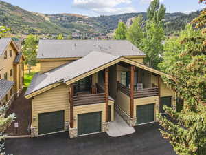 View of front of home with stone siding, an attached garage, a mountain view, a balcony, and driveway