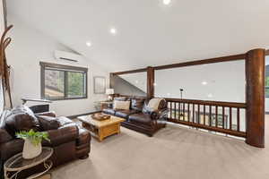 Living area with lofted ceiling, carpet floors, recessed lighting, and a wall mounted air conditioner