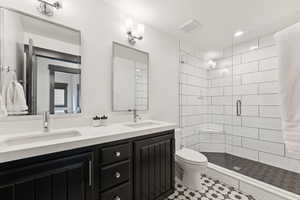 Bathroom with a shower stall, double vanity, recessed lighting, and light tile patterned floors