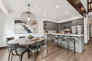 Dining area with light wood-style floors, recessed lighting, and beam ceiling