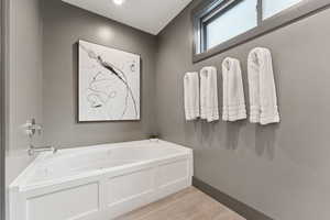 Full bathroom with a bath and light wood-style flooring