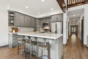 Kitchen featuring gray cabinetry, appliances with stainless steel finishes, decorative backsplash, light wood-style floors, and recessed lighting