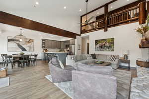 Living room featuring recessed lighting, light wood-style floors, ceiling fan, and a towering ceiling